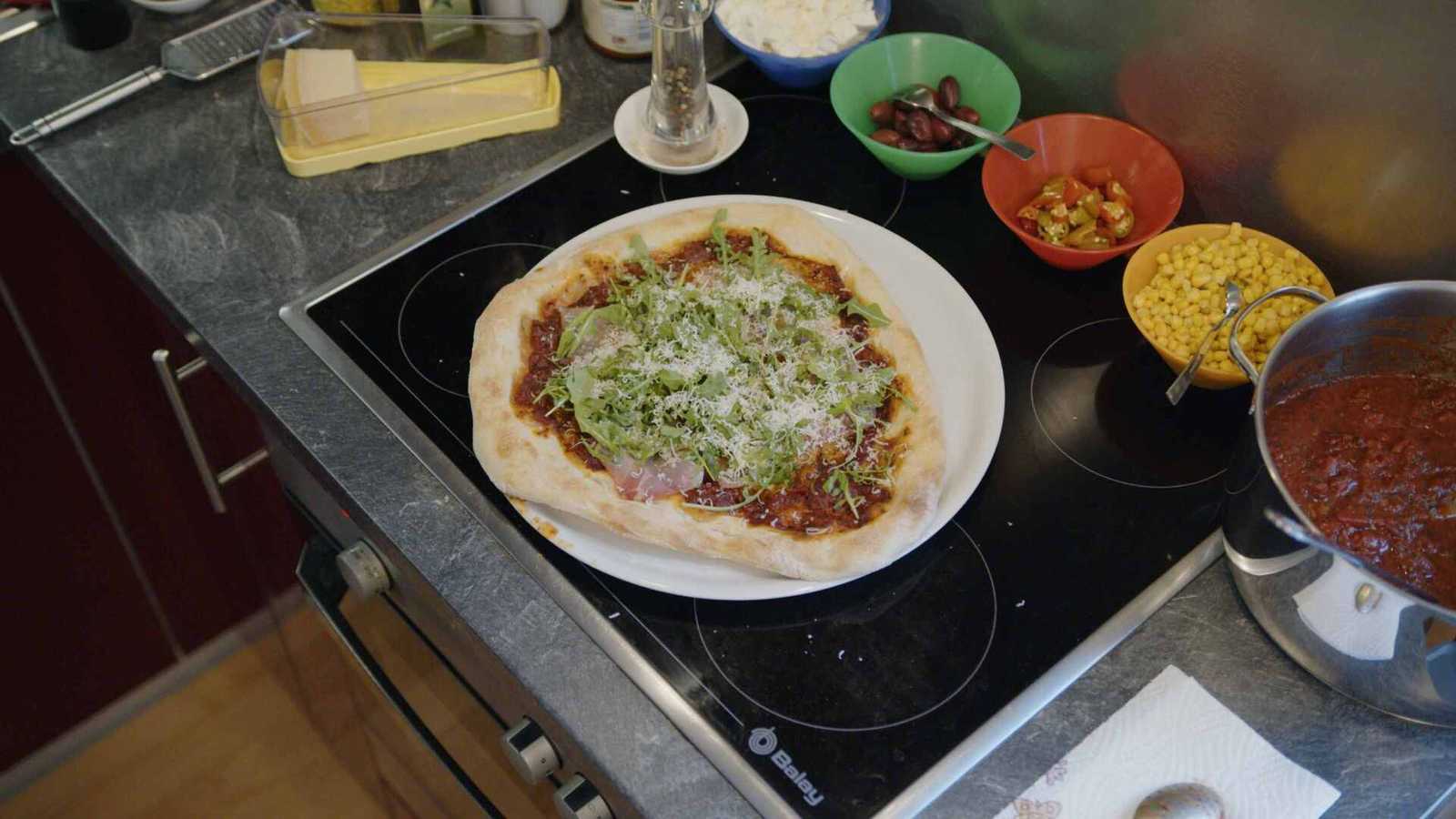 Finished pizza with prosciutto, rocket, pepper, olive oil and parmesan
