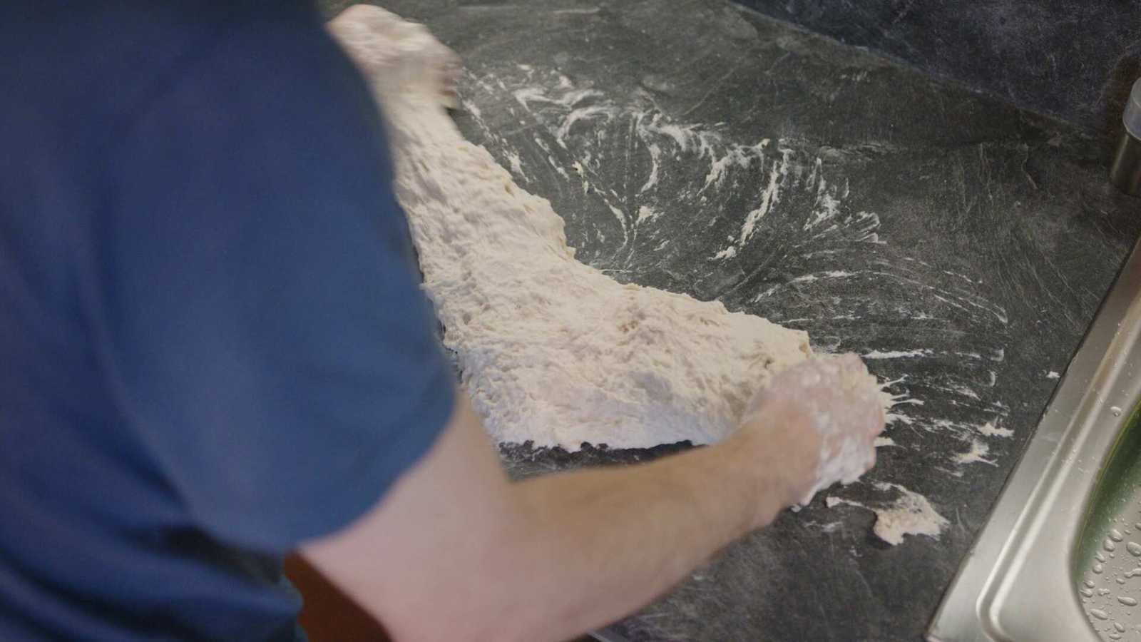 Wet dough being kneaded on work surface