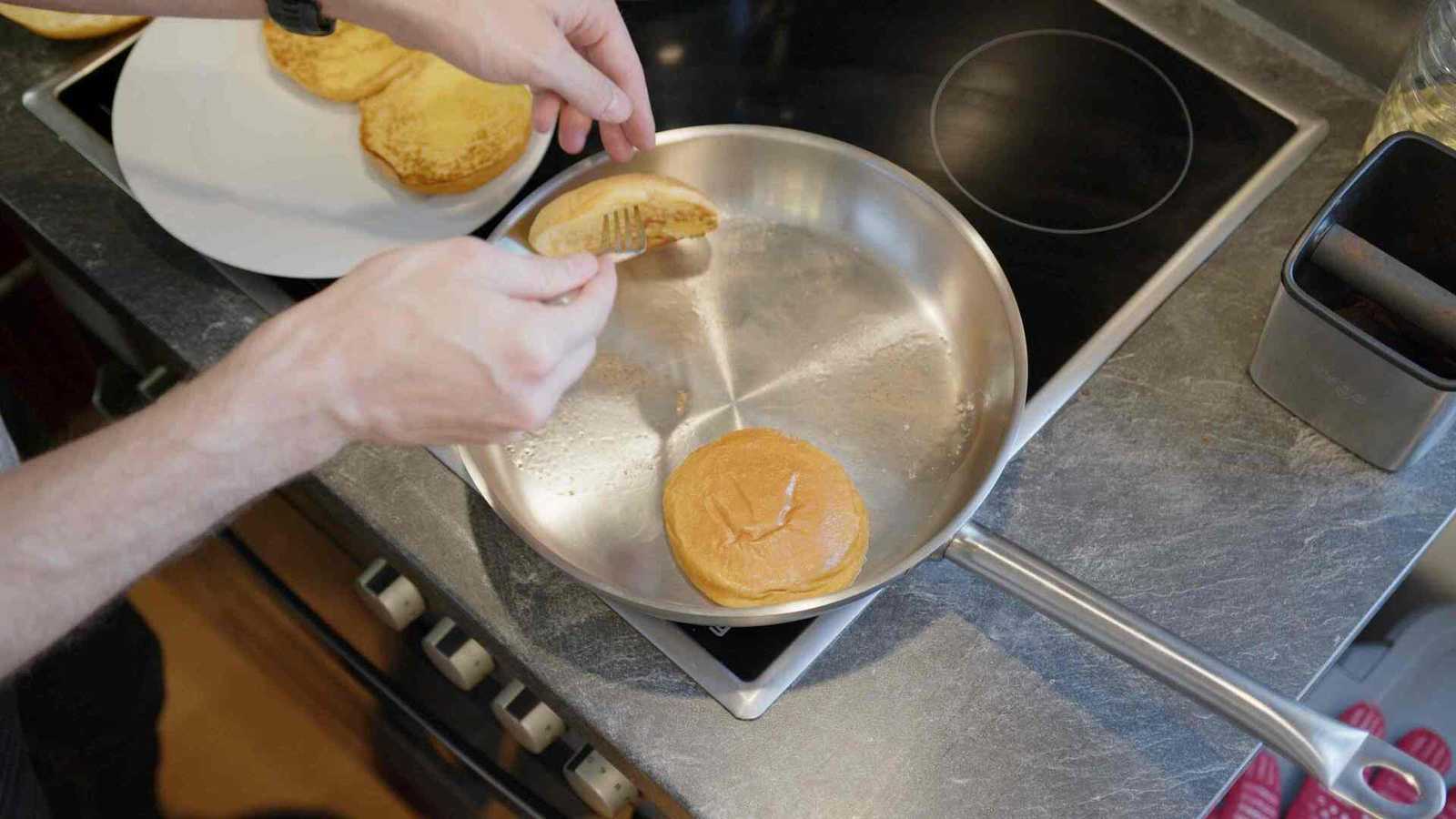 Taking golden brown buns out of a pan