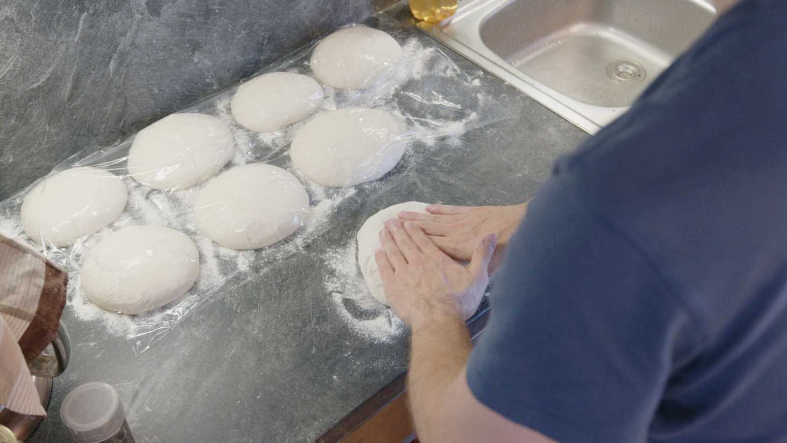 Dough getting pressed into a pizza shape