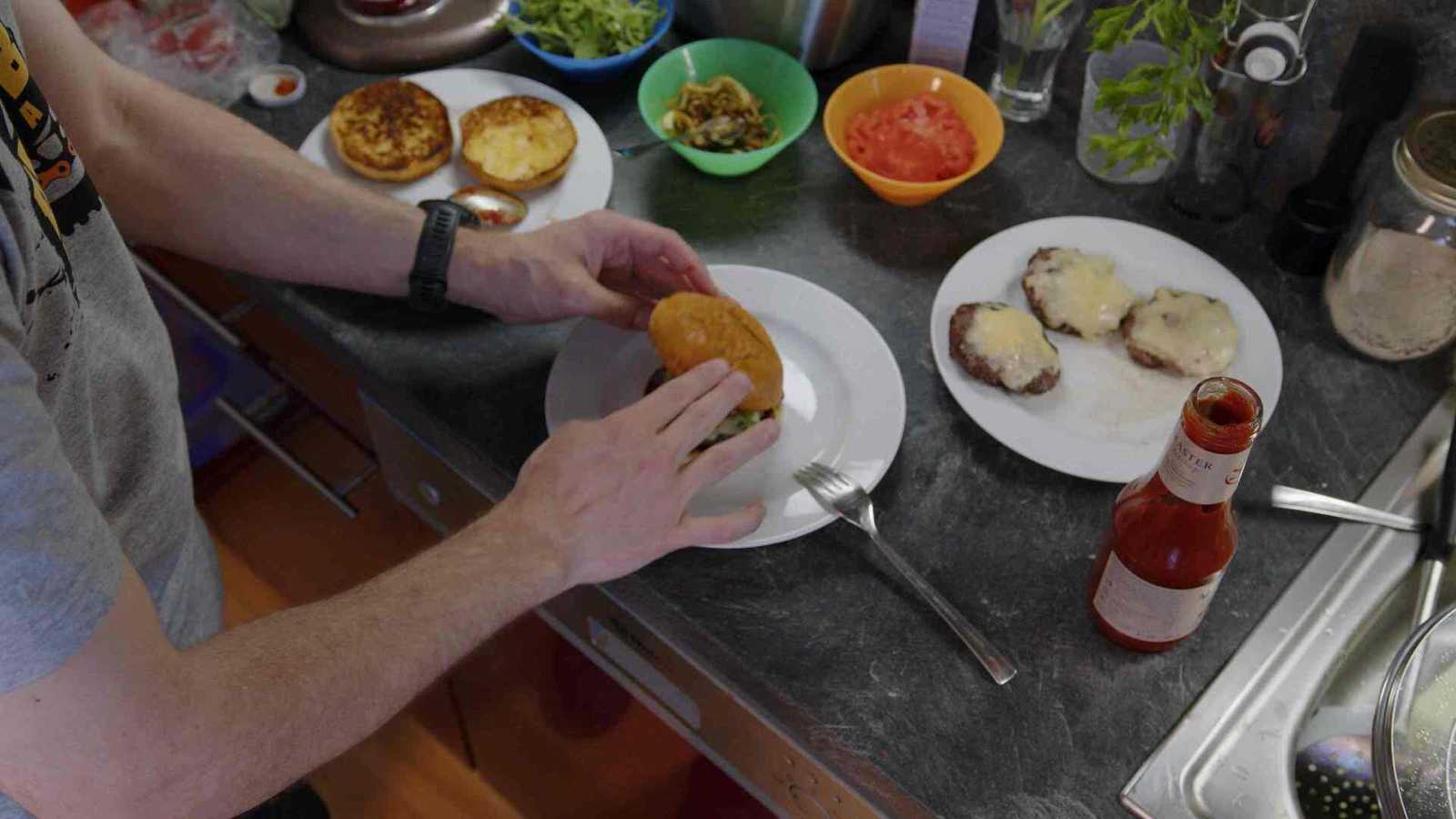 Top bun being put on the rest of the burger